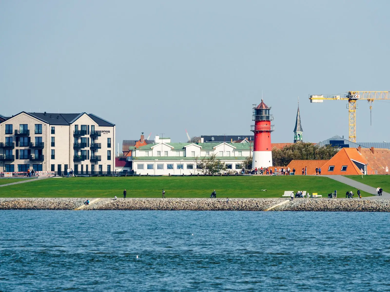 Büsumer Hauptstrand mit rot-weißem Leuchtturm und Hotels, vom Wasser aus gesehen