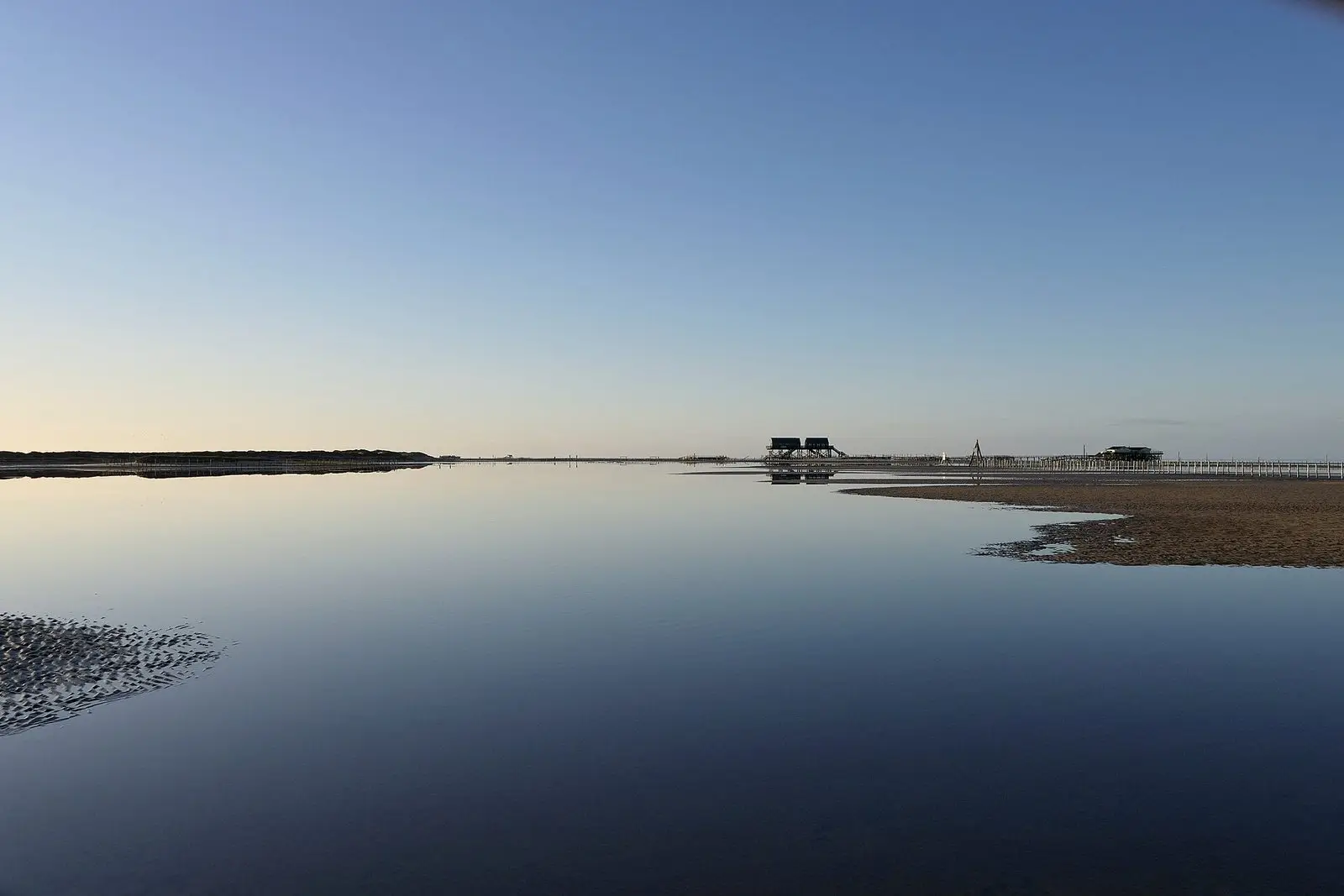 Spiegelglatter Priel am Ordinger Strand bei Ebbe, am Horizont die Pfahlbauten
