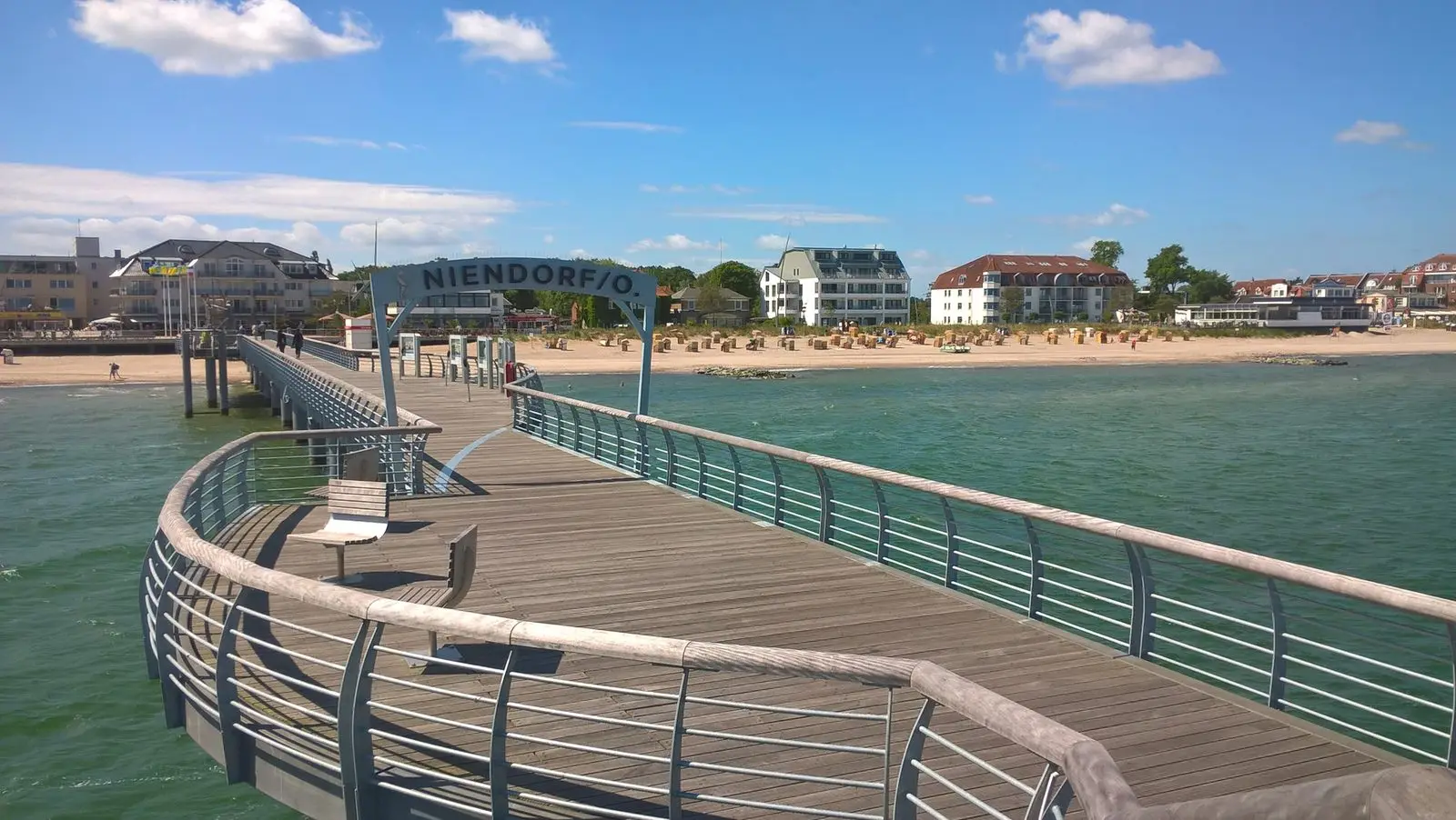 Geschwungene Seebrücke in Niendorf/Ostsee mit Blick auf Strand und Ort