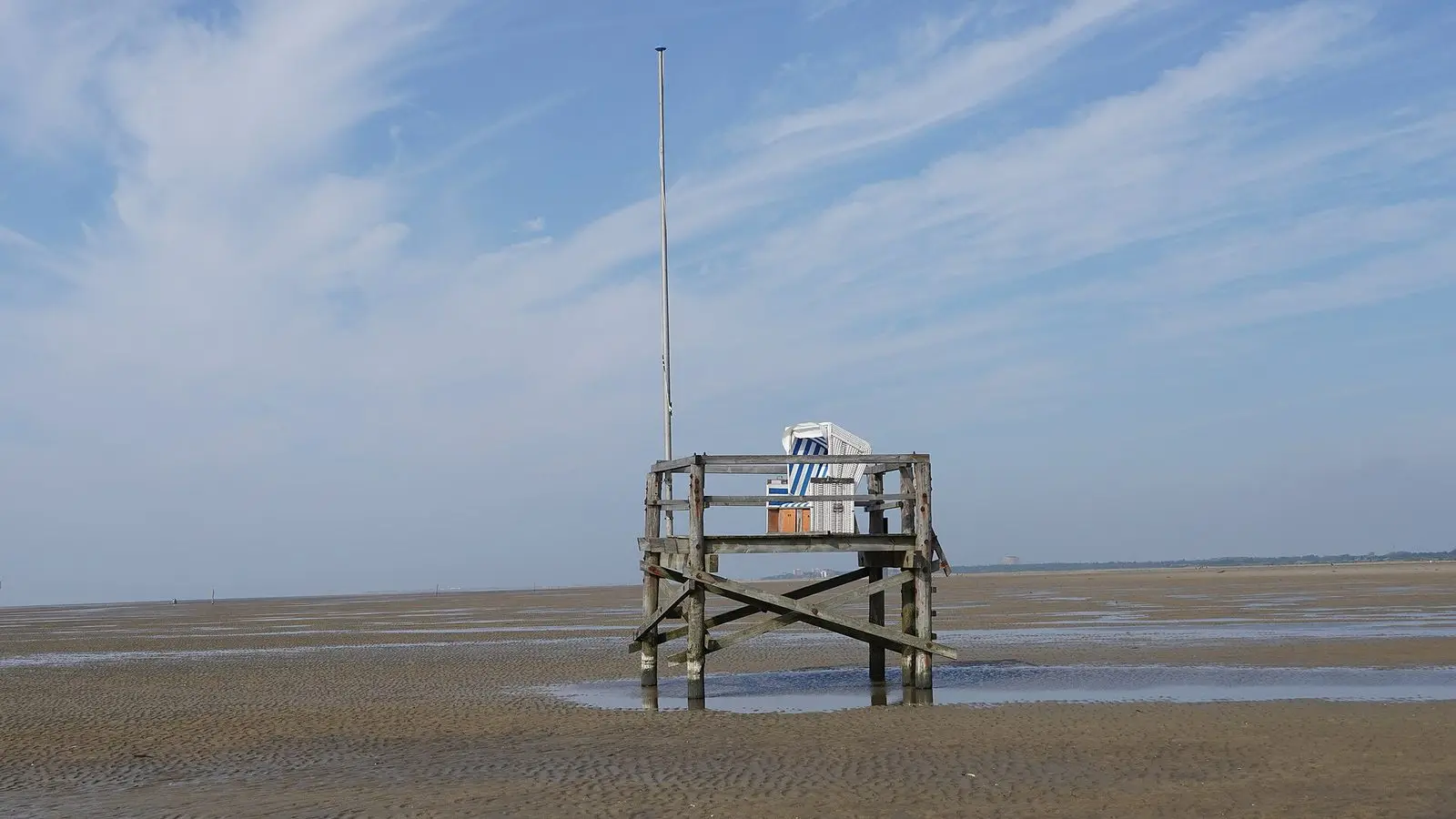 Strandkorb auf einem hölzernen Podest im Watt vor dem Strand von Böhl